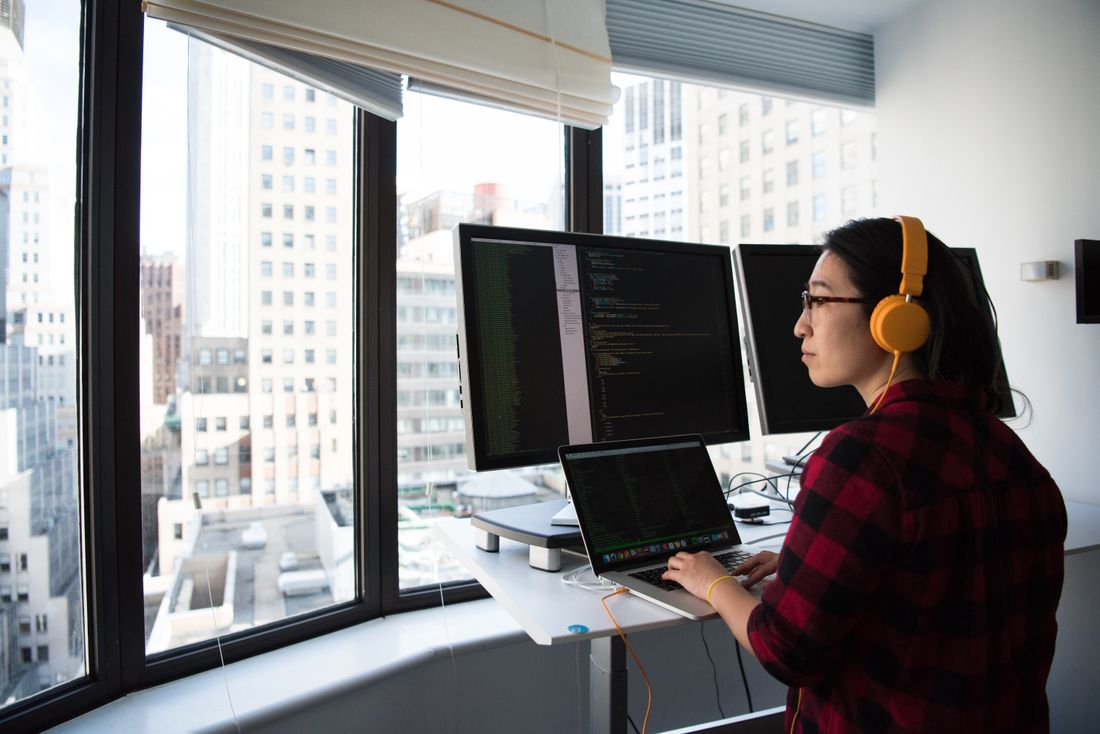 Entwicklerin programmiert eine React-Anwendung an mehreren Bildschirmen